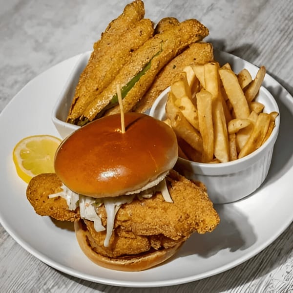 Southern fried fish sandwich with coleslaw, a side of fries, and fried okra on a white plate.