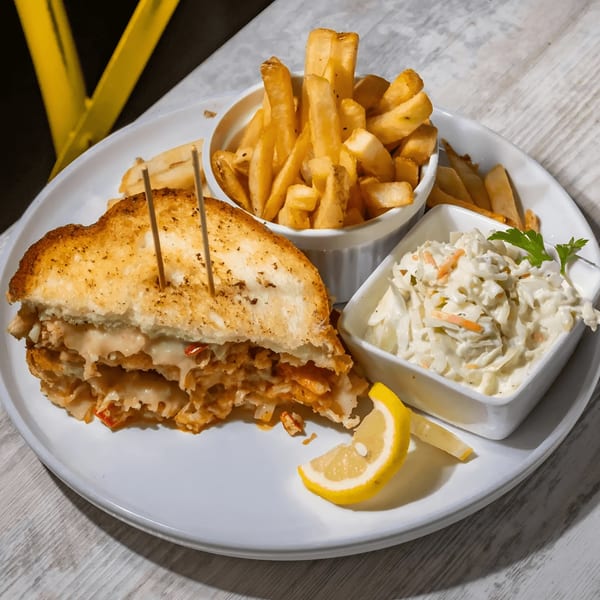 Southern grilled cheese with fries and coleslaw, garnished with a lemon wedge and parsley.
